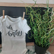 Load image into Gallery viewer, white infant onsie with "oh baby" printed in black HTV vinyl made in Sherwood Park Alberta by All Decked Out Event