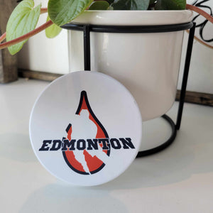 Smooth matte finish ceramic coaster with the word "Edmonton" written in black overlaid on the outline of a hockey player in an Oilers oil drop. Bumper dots on the bottom