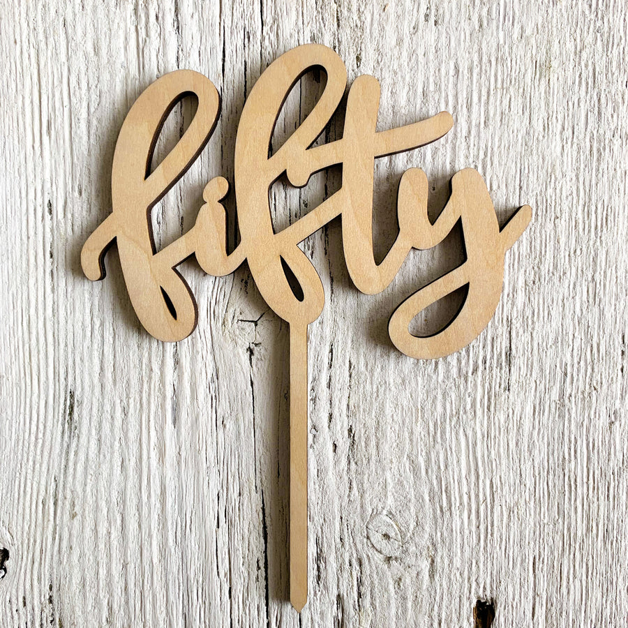 Laser engraved wooden cake topper that says "fifty".