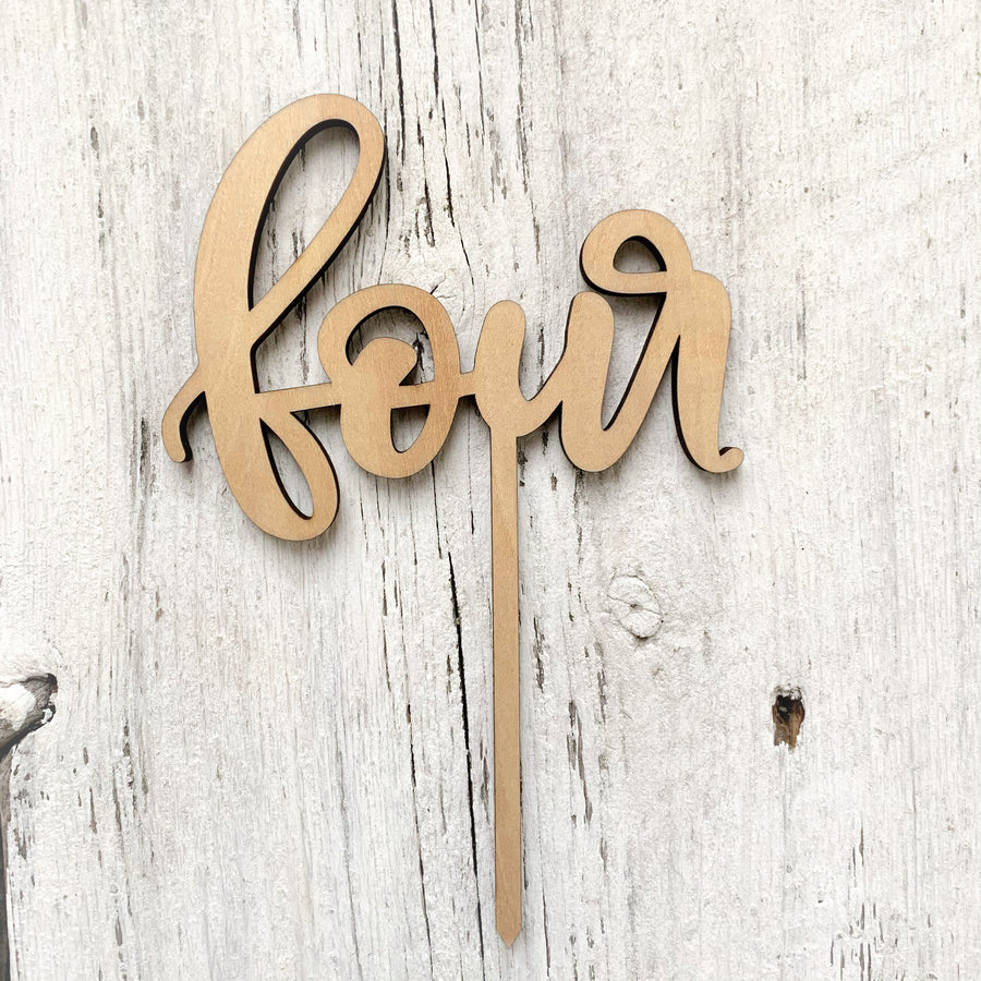 Laser engraved wooden cake topper with the word "four".