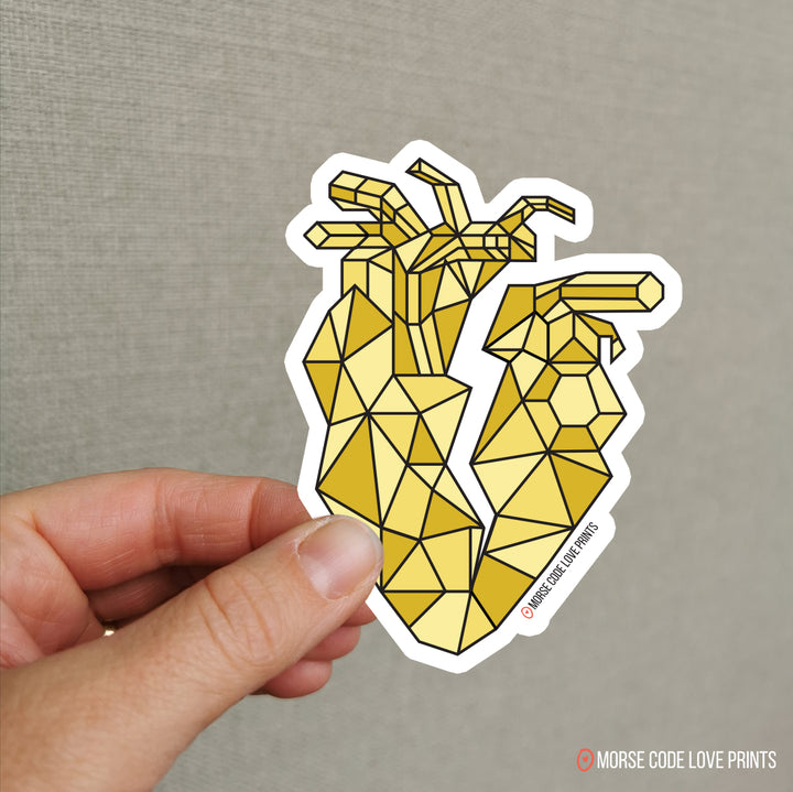 A vinyl sticker of a yellow geometric anatomical heart with a crake in the middle