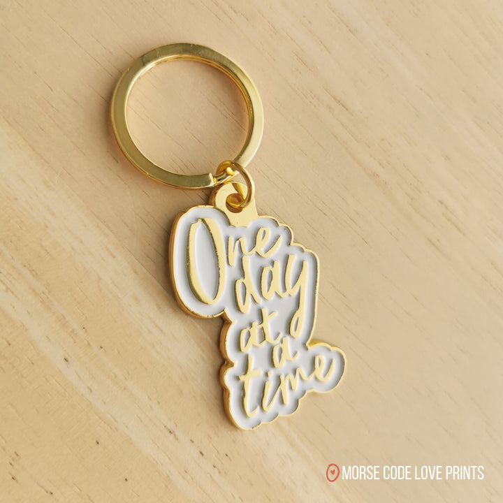 Each "One Day At a Time" pendant has a white background and measures 1.75" on the longest/widest edge. Additionally is the keyring and one jump ring.