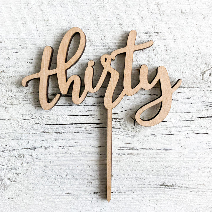 Laser engraved wooden cake topper of the word "thirty".