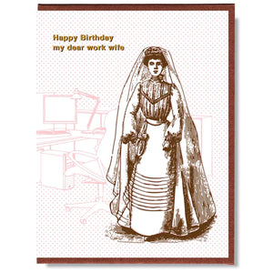 This A2 size (4.25” x 5.5”) birthday card is digitally printed and gold foil pressed, is blank inside and comes with a recycled envelope. The front of the card has a woman dressed in vintage clothes and says "Happy birthday my dear work wife" in gold lettering.