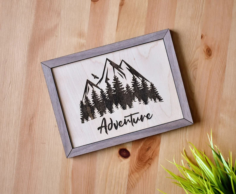 Beautiful decor sign made of high-quality maple plywood that is carefully laser engraved with our own Adventure and Nature-inspired art design. The sign is nicely finished with a walnut frame. A mounting hole is provided for quick and easy installation.